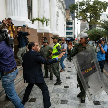 a man in a suit faces a law enforcement officer in riot gear